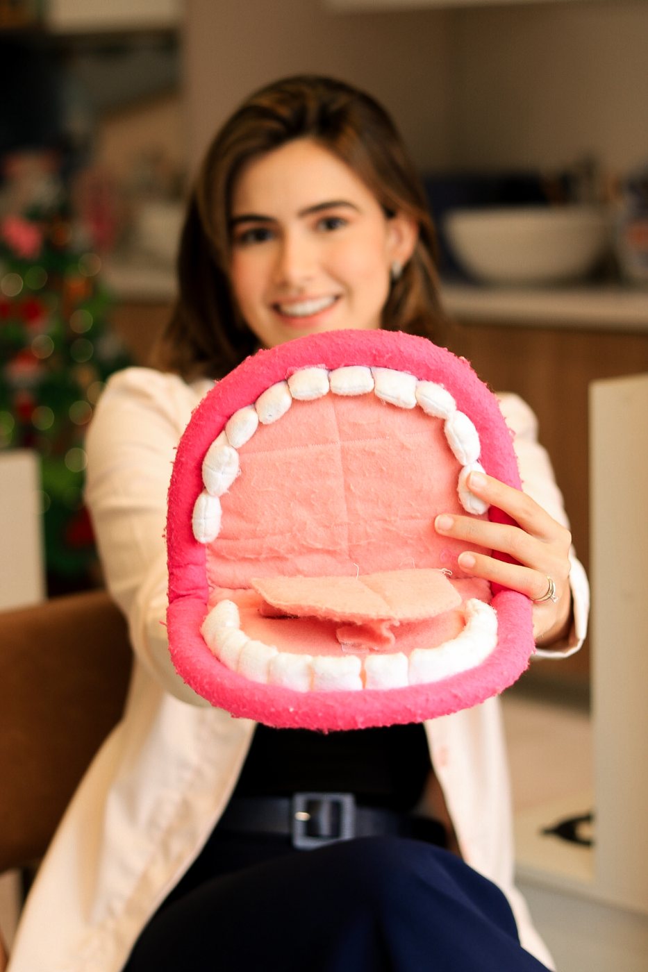 Alice Guedes sorrindo e segurando um modelo de boca em pelúcia